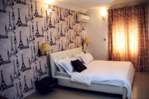 a bedroom with a white bed with a black and white wall at Lukeville Suites in Abuja