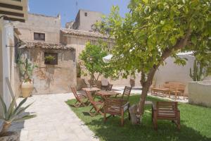 a patio with a table and chairs under a tree at Welcome Garden in Noto
