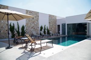 a pool with chairs and a table and an umbrella at Hotel Florença in Americana