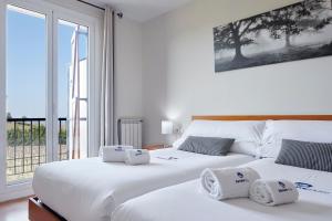 Habitación con 2 camas blancas y ventana grande. en Casa Rural Xabin Etxea - Basque Stay - XSS00041, en Getaria
