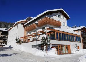 a large building with snow on the ground at Conrad's Mountain Lodge in Silvaplana