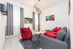 - un salon avec un canapé gris et des fauteuils rouges dans l'établissement TNT Apartment, à Zadar