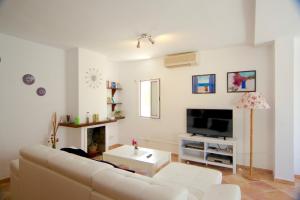 a living room with a white couch and a tv at Beach Villa Carmen in Playa de Muro