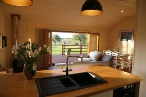 a kitchen with a sink and a living room at Honeysuckle in Hadleigh