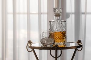 a bottle of whiskey and a glass on a table at Panorama-27 Jacuzzi Apartment by LIUKSAI in Klaipėda