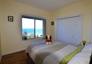 pies siedzący na łóżku w sypialni z oknem w obiekcie Gibralter Rock Ocean View B&B w mieście Nanaimo