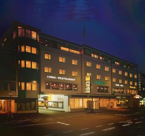 ein großes Gebäude mit nachts eingeschaltetem Licht in der Unterkunft Hotel Central in Weil am Rhein