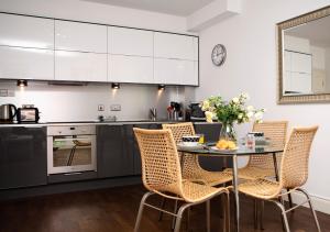 a kitchen with a table and chairs in a kitchen at Apt 2, Trafalgar Square 2nd Floor by Indigo Flats in London