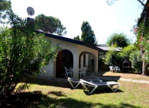 a house with a yard with a chair and a table at Ville Park Hotel in Bibione