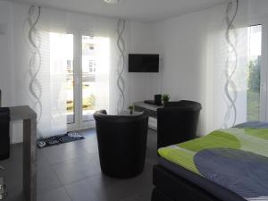a bedroom with a bed and two chairs and a tv at Ferienapartment im Augustinus Park in Trier