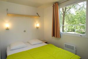 a bedroom with a green bed and a window at Camping la Croix du Sud in Saint-Tropez