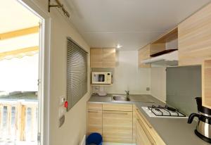 a small kitchen with a sink and a microwave at Camping la Croix du Sud in Saint-Tropez
