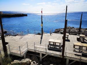 a wooden pier with chairs and the ocean at Masseria Fachechi in Nardò