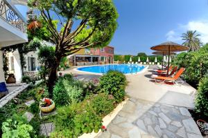 a swimming pool with chairs and an umbrella at Alkyon Apartments & Villas Hotel in Lygia