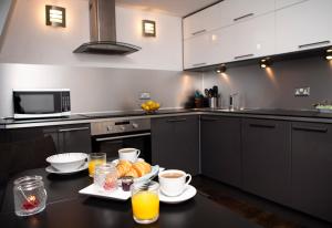 cocina con mesa y plato de comida en Apt 3, Trafalgar Sq Duplex, 3rd & 4th floor by Indigo Flats, en Londres