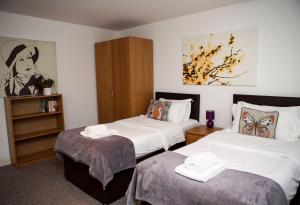 a room with two beds and a book shelf at Apt 3, Trafalgar Sq Duplex, 3rd & 4th floor by Indigo Flats in London