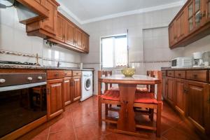 a kitchen with a table with chairs and a washing machine at Casa Do Gerardo in Nazaré