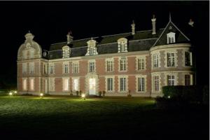 ein großes Backsteingebäude in der Nacht mit Lichtern in der Unterkunft Château de Behen in Béhen