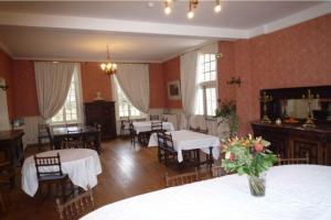 un comedor con mesas y sillas blancas y ventanas en Château de Behen, en Béhen