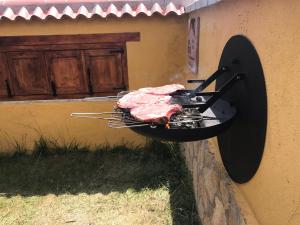 una parrilla al lado de un edificio con carne en él en Gredos Casa Rural Los Treboles, en San Martín de la Vega del Alberche