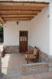 a porch with a bench and a wooden door at El Zorro Gris in Tinogasta