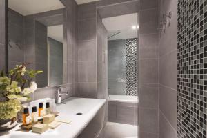 La salle de bains est pourvue d'une baignoire blanche et d'un lavabo. dans l'établissement Hôtel Belloy Saint Germain, à Paris