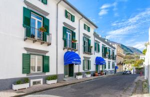 uma rua em uma cidade com prédios brancos com persianas verdes em Hotel Terme Miramonte e Mare em Ischia