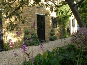 a garden with purple flowers and a black door at Threeways House in Daventry