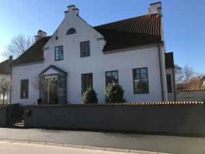 a white house with a fence in front of it at Charmigt i centrala Ystad in Ystad