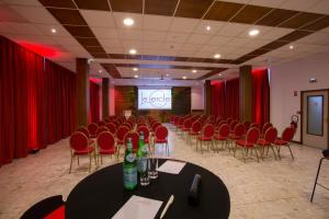 a conference room with red chairs and tables and a screen at Hotel Le Cercle in Cherbourg en Cotentin