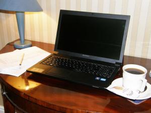 a laptop computer sitting on a desk with a cup of coffee at Threeways House in Daventry