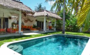 a swimming pool in front of a house at Villa Rustic Charm in Gili Trawangan