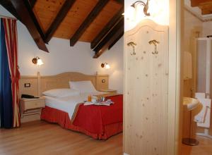 a bedroom with a bed and a bathroom with a sink at Hotel Cant del Gal in Fiera di Primiero
