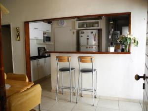 una cocina con 2 taburetes en un bar con nevera en Casa de alquiler San Juan en San Juan