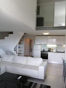 a living room with a white couch and a kitchen at Apartment Osk in Osijek