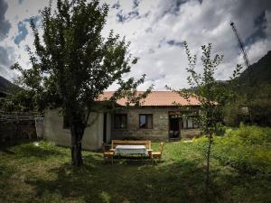 a house with a table and a tree in the yard at Keti Pilpani Guesthouse in Mestia