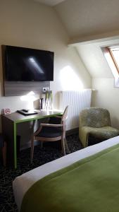 a room with a bed, desk and television at Hotel Le Cercle in Cherbourg en Cotentin