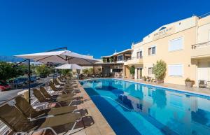 a swimming pool with chairs and umbrellas next to a building at Veronica Hotel in Kato Daratso