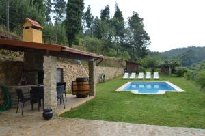 einen Hinterhof mit Pool und Stühlen und ein Haus in der Unterkunft Casa do Ribeiro in Sever do Vouga