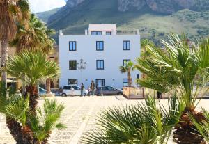 un edificio blanco con palmeras delante en Residence Itaca, en Castellammare del Golfo