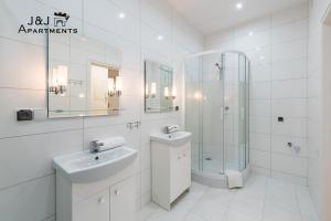 biała łazienka z umywalką i prysznicem w obiekcie J&J Apartments Łazienna 30 Pensjonat 10 w Toruniu