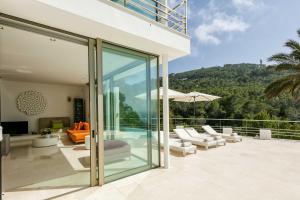 a house with glass doors and a patio with furniture at Villa Vadella by Eivillas in Cala Vadella