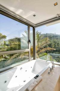 a bath tub in a bathroom with a large window at Villa Vadella by Eivillas in Cala Vadella