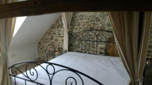 a bed in a room with a stone wall at La Ferme Blanche in MÃ©nil-Vin