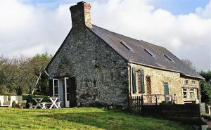 an old stone building on a grass field at La Ferme Blanche in MÃ©nil-Vin
