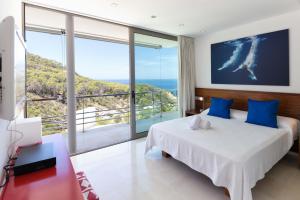 a bedroom with a bed and a large window at Villa Vadella by Eivillas in Cala Vadella +26 photos
