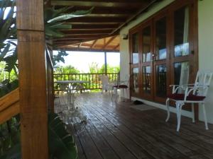 a wooden deck with white chairs and tables on it at The Pool House in Saint Philip