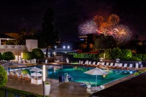 - une piscine la nuit avec feux d'artifice en arrière-plan dans l'établissement Anaheim Hotel, à Anaheim
