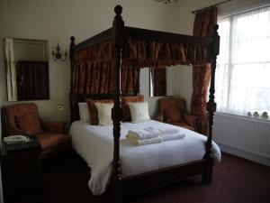 a bedroom with a canopy bed with towels on it at The Bell Hotel in Winslow