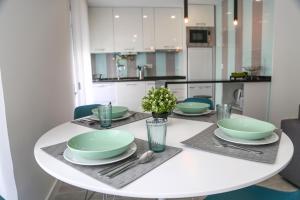 a white dining room table with green dishes on it at Casa da Mari Julia in Nazaré